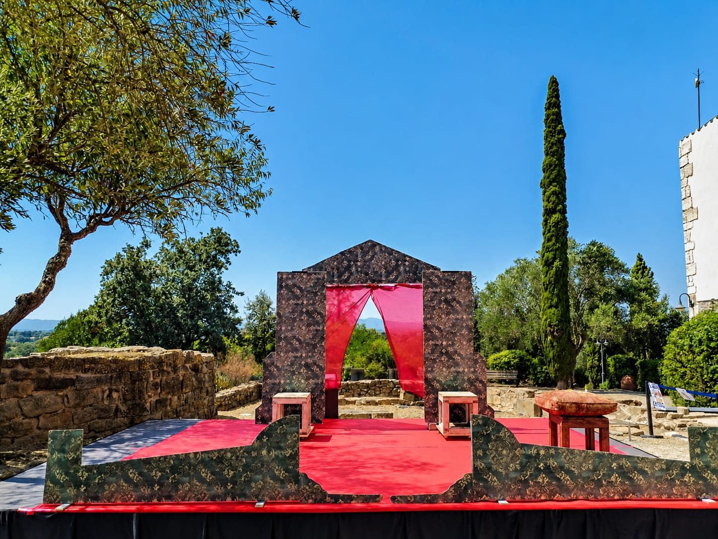 Jardí amb un arc de pedra i un teló vermell convertit en escenari