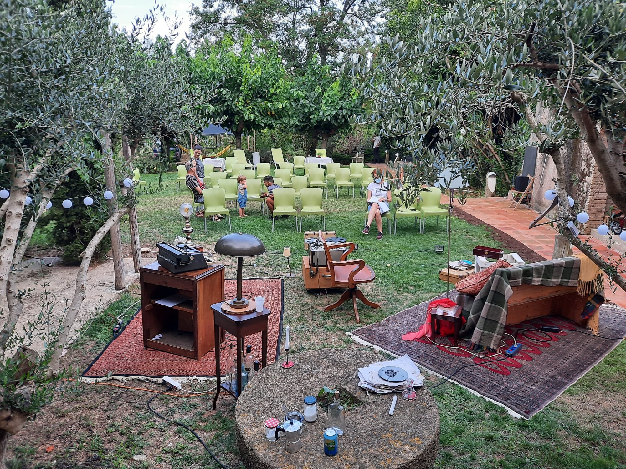 Jardí d'oliveres amb catifes i cadires per al públic