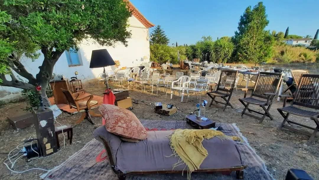 Jardí amb un sofà i catifes com a escenari, envoltat de cadires