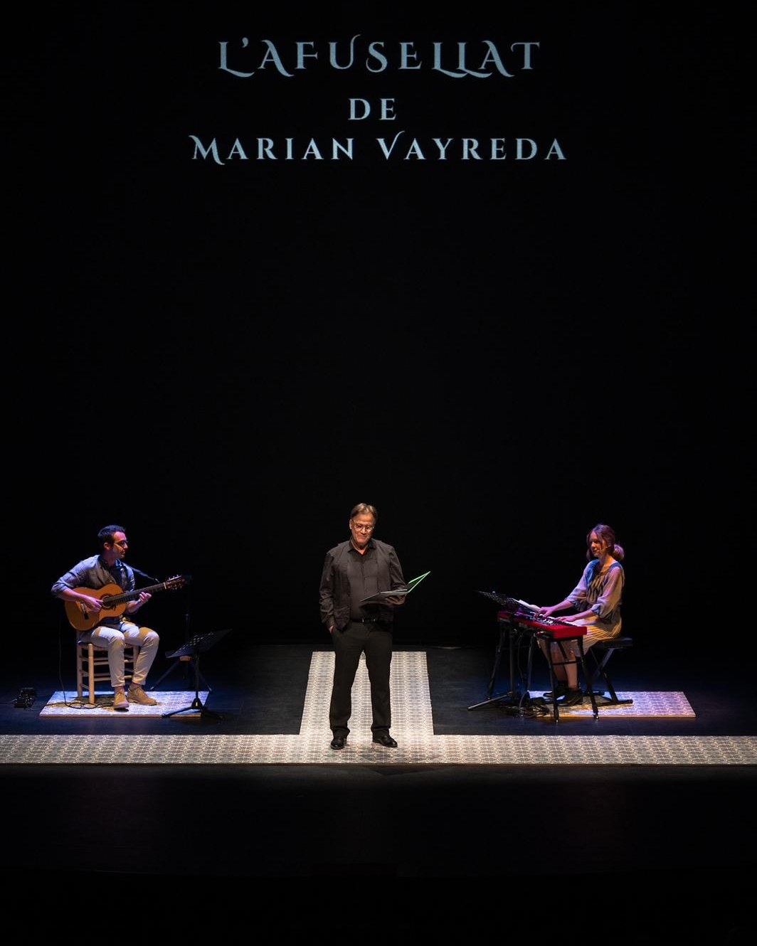 L'afusellat: Martí Peraferrer llegint a l'escenari, amb Marcel Torres a la guitarra i Glòria Vila al piano